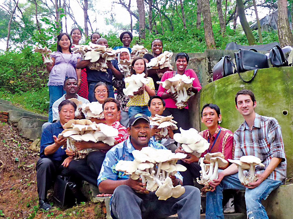 　　圖：林占熺（第二排左一）在非洲農戶種植菌菇喜獲大豐收後，與農戶合影。\受訪者供圖