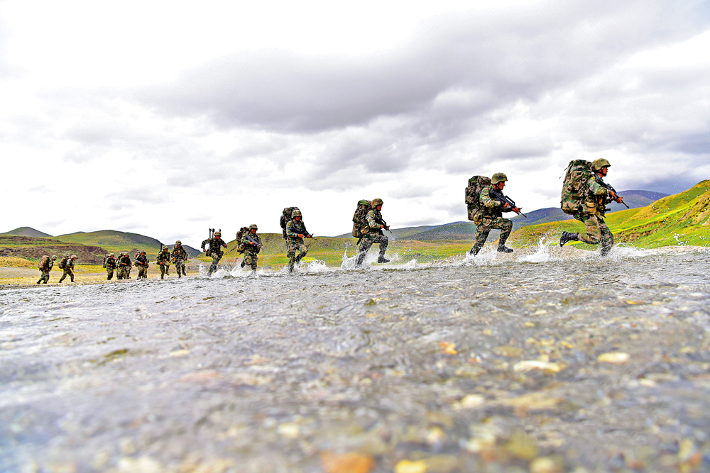 　　圖：西藏軍區官兵在日常巡邏時揹着背囊穿越溪流。\中國軍網