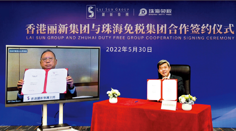 　　圖：會上，珠海免稅集團董事長魯君駟與麗新集團主席林建岳通過視頻簽署合作協議，雙方高層共同見證簽約儀式。