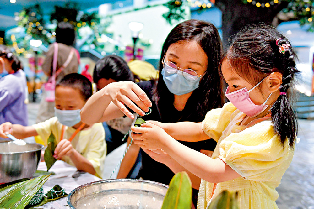 　　圖：6月5日，家長帶着小朋友在杭州市青少年活動中心體驗製作糉子。\新華社