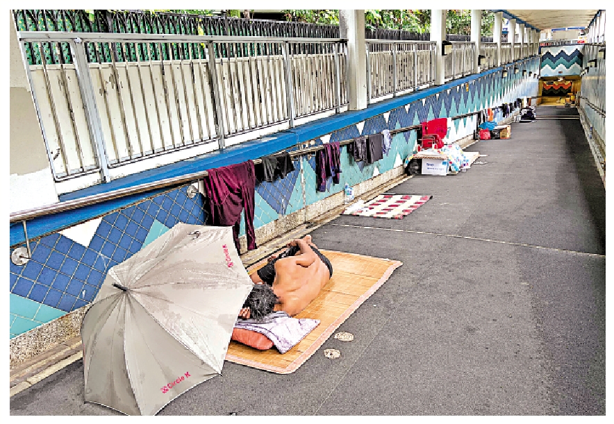 　　圖：雨從外面飄進隧道，睡在櫻桃街行人隧道的露宿者只能靠雨傘遮擋。