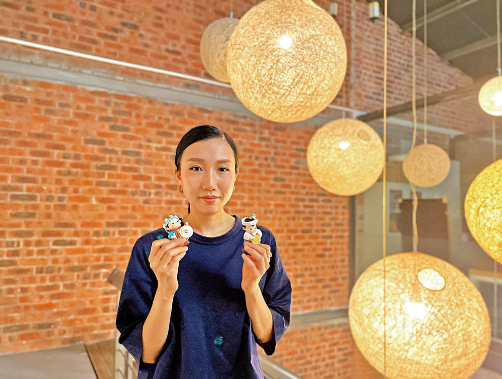 　　圖：鄧卓越向記者介紹民族娃娃的創作過程。 大公報記者胡永愛攝