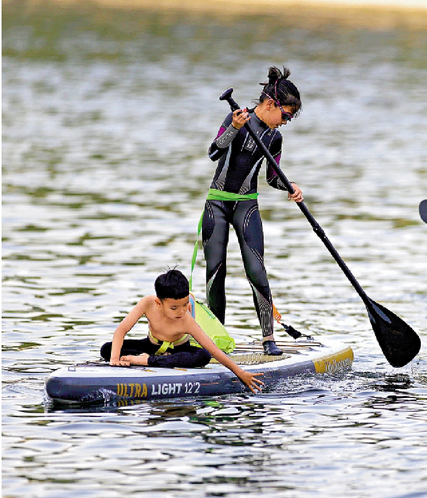 　　圖：小朋友在北京東城區一河道內划槳板戲水納涼。\中新社