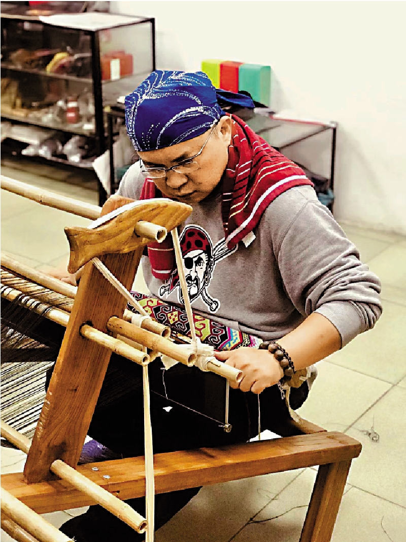 　　圖：酷愛傳統工藝的台灣設計師林俊億專心在傳統腰織機前織布。\受訪者供圖