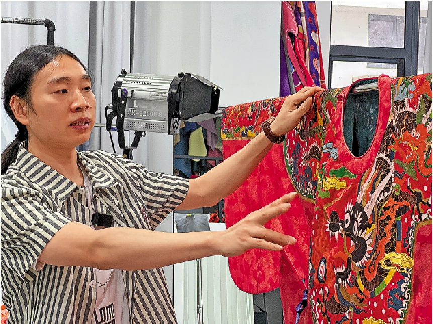 　　圖：鍾毅向記者介紹雲肩通袖圓領蟒袍的設計思路和寓意。\大公報記者黃寶儀攝