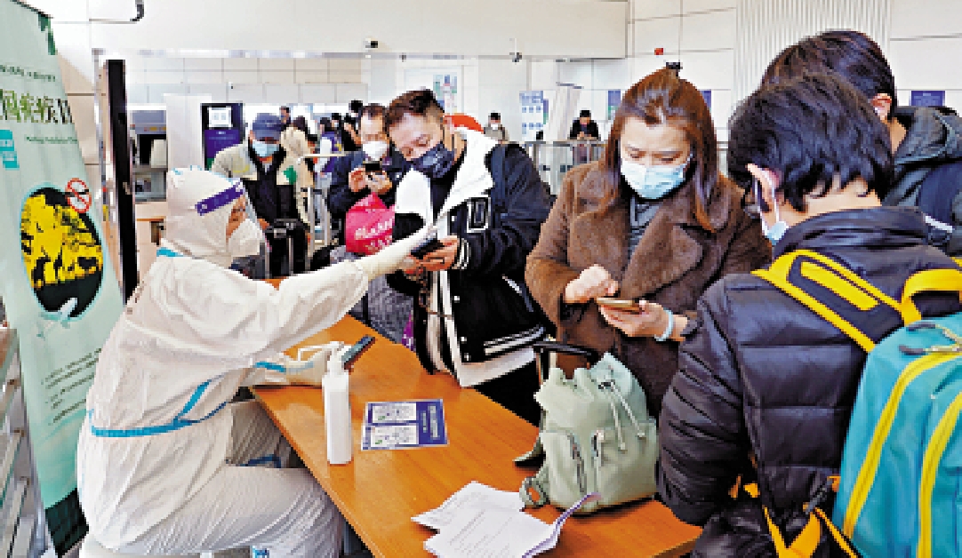 　　圖：深圳口岸出境大廳工作人員在為旅客指引如何填寫海關健康申報。\大公報記者 郭若溪攝