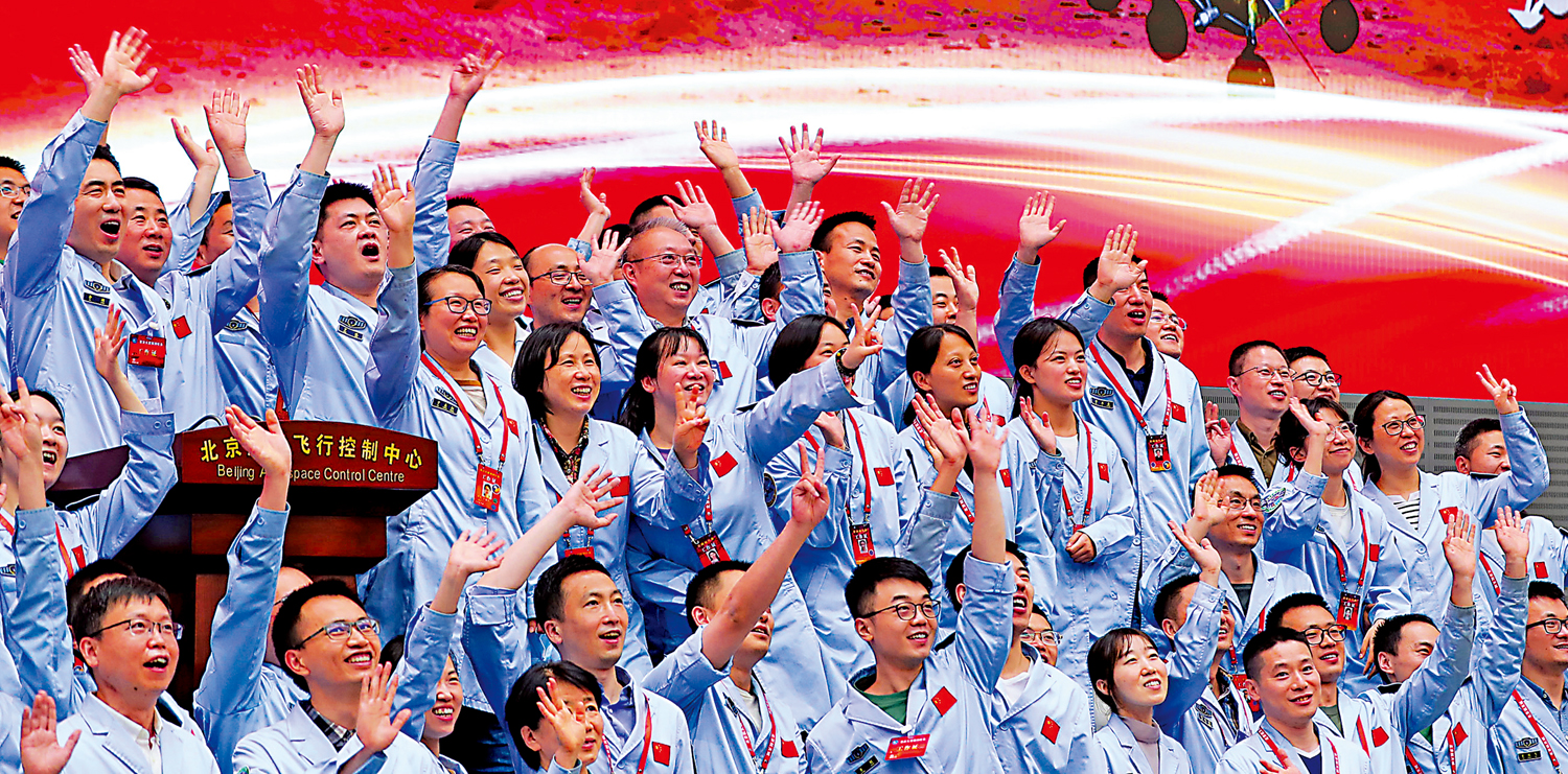 　　圖：在北京航天飛控中心指揮大廳，航天科研人員慶祝中國首次火星探測任務着陸火星成功。\新華社