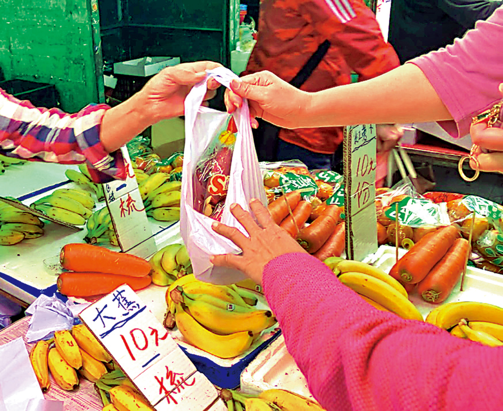　　圖：有市民在街市購買一袋已包裝好的番薯，商戶習慣性地送多一個膠袋給顧客，不過事實上，他們已經違法。\大公報記者鍾佩欣攝