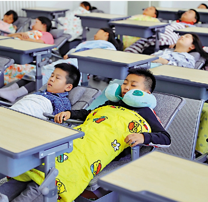 　　圖：河北省秦皇島市某小學學生使用可調節午休課桌椅休息。