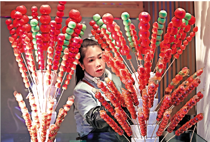 　　圖：北京煙袋斜街上，一名店員整理攤位上的糖葫蘆。/中新社