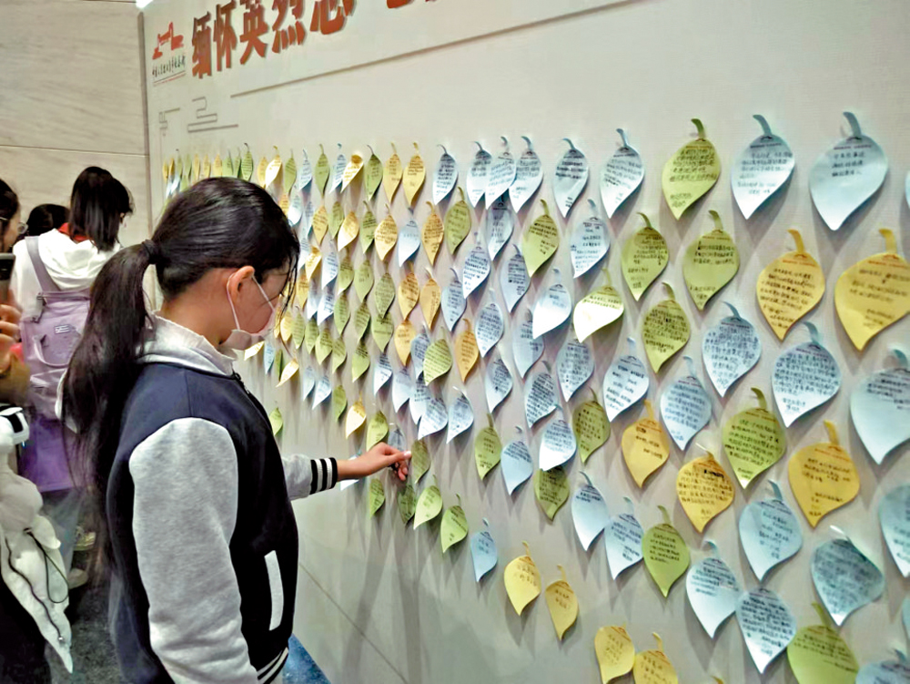 　　圖：參加紀念活動的學生在留言牆留言。\大公報記者馬曉芳攝