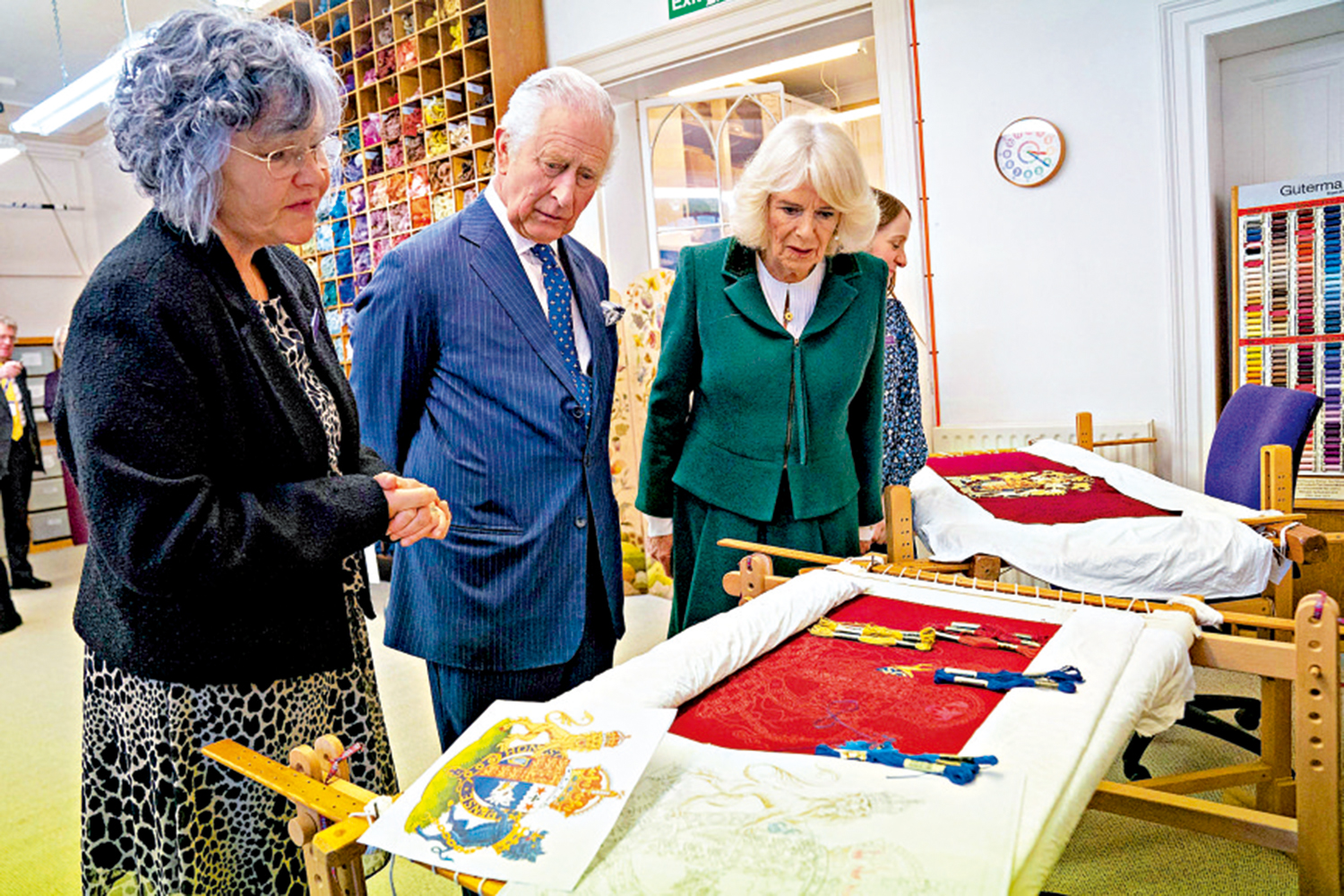 　　圖：英王查爾斯三世（中）和王后卡米拉（右）檢視製作中的王座椅套。\法新社
