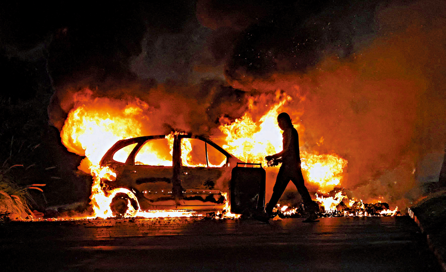 　　圖：6月30日，一名暴徒在法國屬地留尼旺群島的勒波爾街頭縱火燒毀一輛汽車。\法新社
