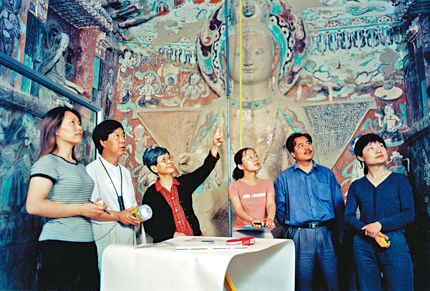 　　圖：樊錦詩至今已從事敦煌文物事業整整60年。圖為2004年，樊錦詩在石窟內指導青年人進行研究工作。