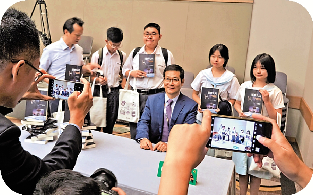 　　圖：趙小津（中）為香港青年學生簽書及合影。