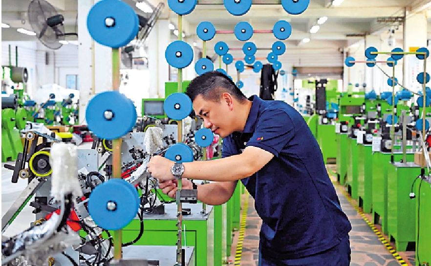 　　圖：劉偉立在生產車間內檢查拉鏈機械設備。\中新社