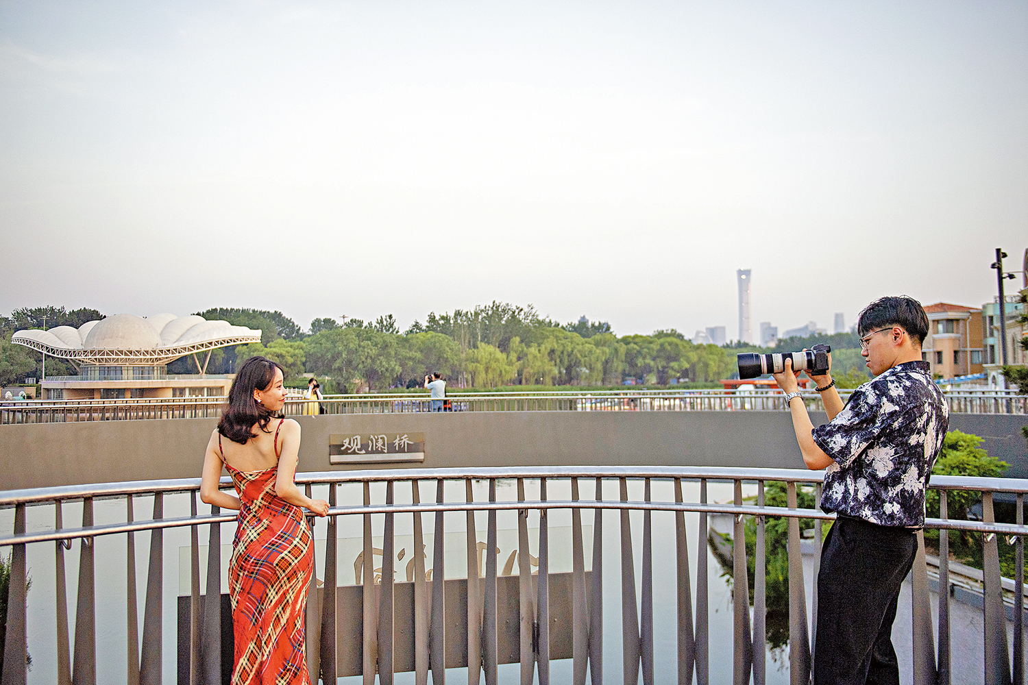 　　圖：Citywalk從線上火到線下，成為中國年輕人流行的休閒方式。圖為兩名年輕人在北京亮馬河畔悠閒遊覽拍照。\新華社