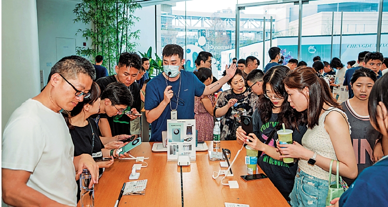 　　圖：眾多顧客在產品展台前試用新發布的華為5G手機。