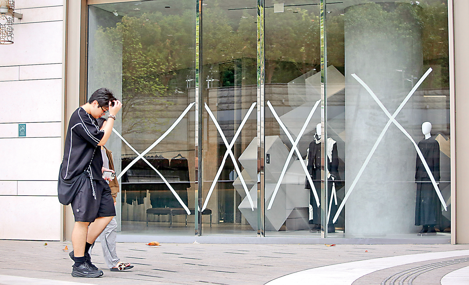 　　圖：「小犬」迫近香港，天文台考慮今日下午會否改掛八號風球，商舖做足準備，在櫥窗貼上膠帶防風。\大公報記者麥潤田攝