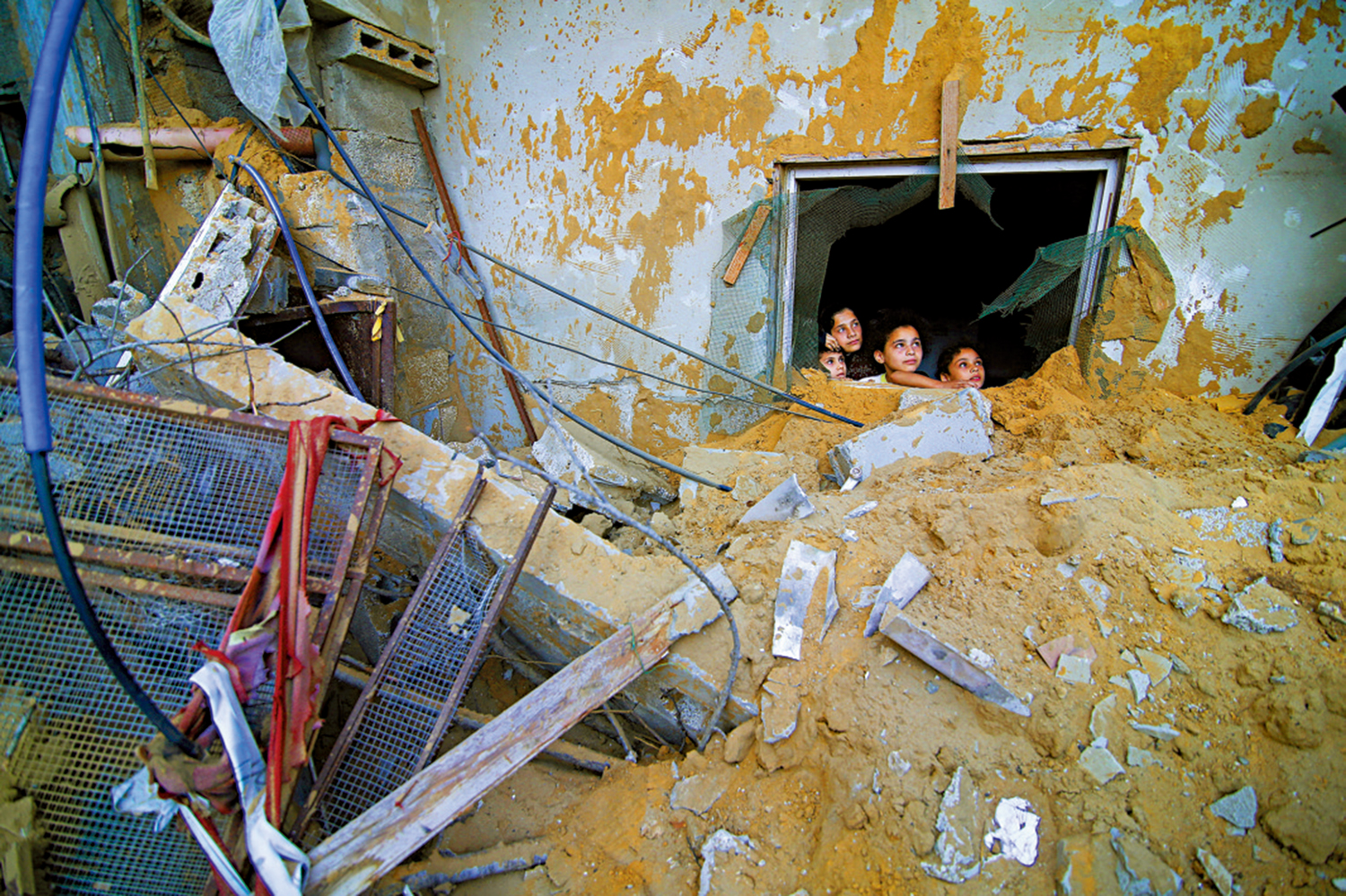 　　圖：14日，巴勒斯坦兒童躲在被以色列空襲摧毀的廢墟中。\美聯社