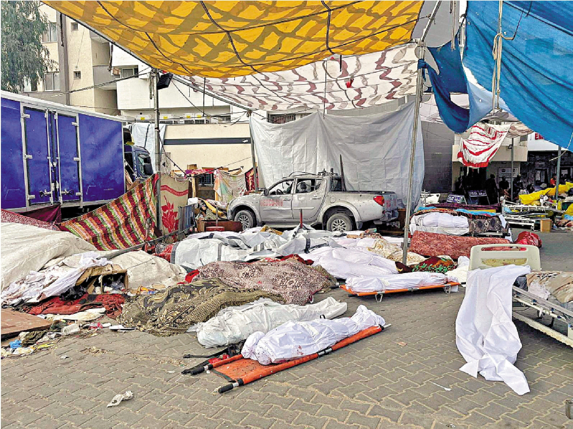 　　圖：在以軍攻入希法醫院前，醫院大樓前的空地上堆積了大量遇難者遺體。\路透社