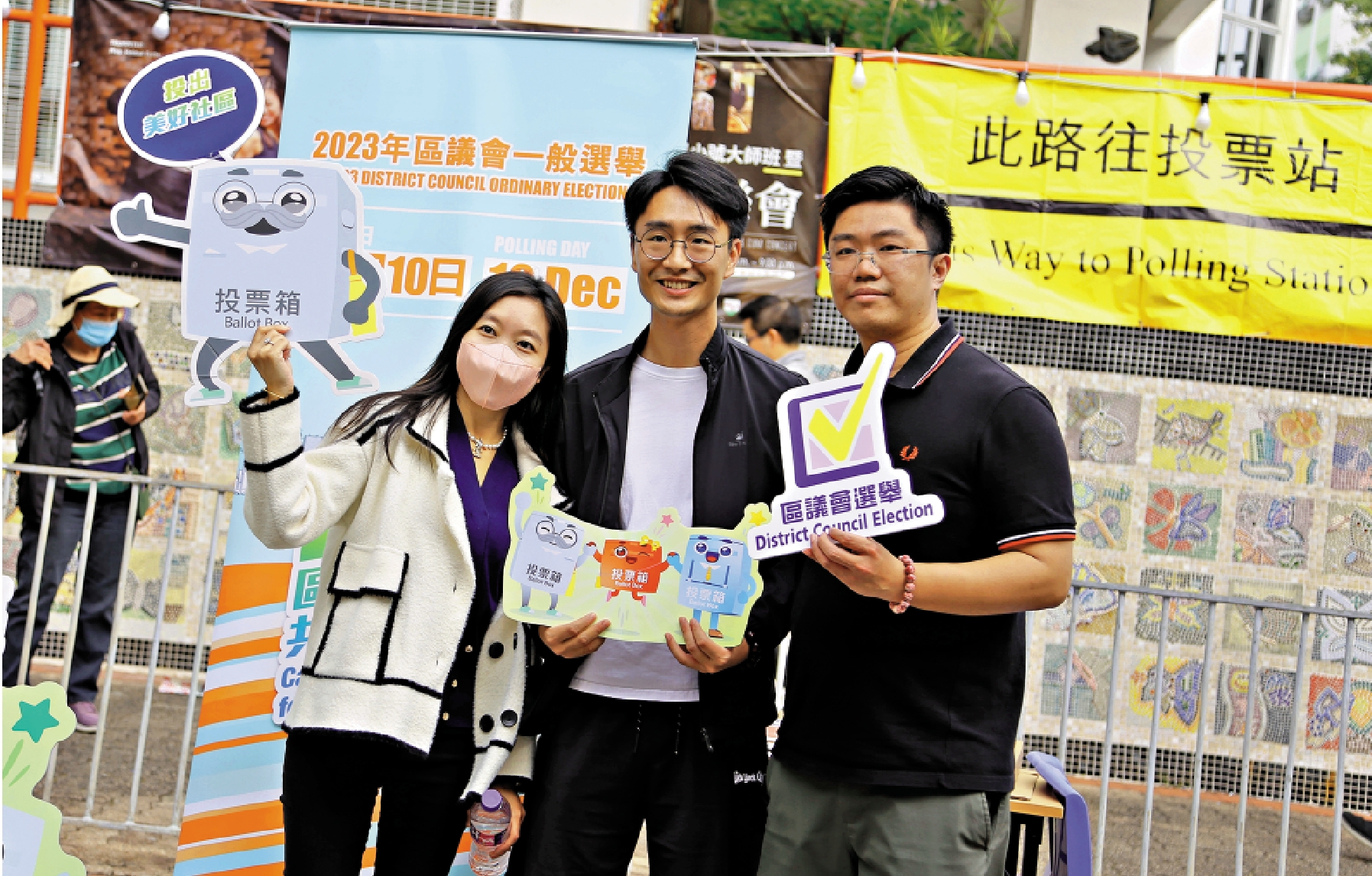 　　圖：在上水鄰近邊境投票站，數名選民手持卡通紙板打卡留念。\大公報記者何嘉駿攝