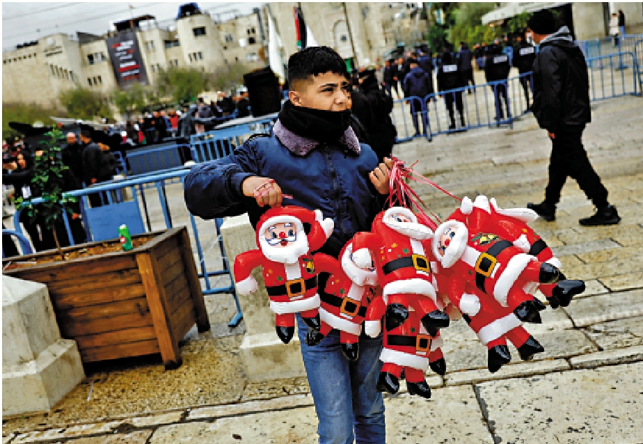 　　圖：一名男孩24日在伯利恆馬槽廣場售賣聖誕老人氣球。\路透社