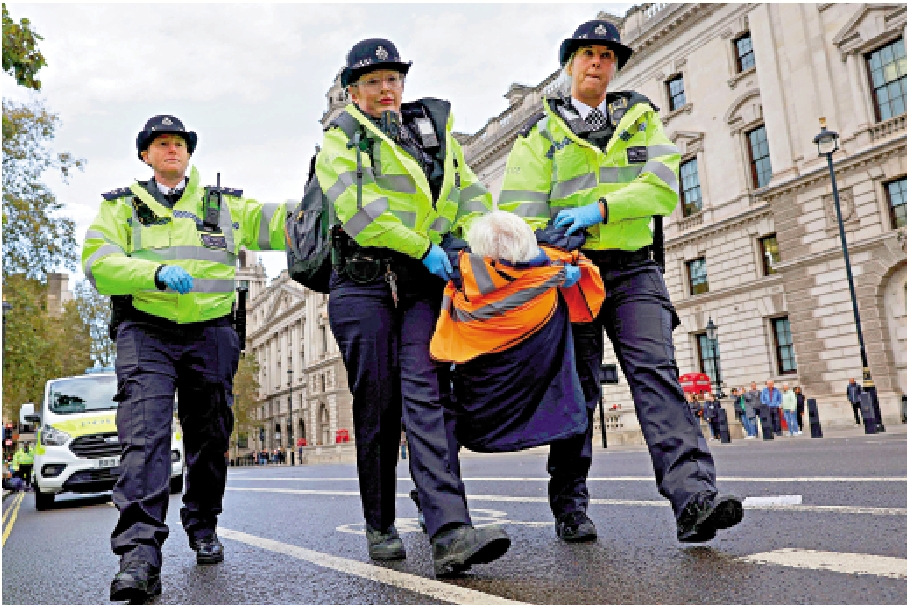　　圖：2023年10月，英國警察逮捕一名阻塞交通的環保團體示威者。\法新社