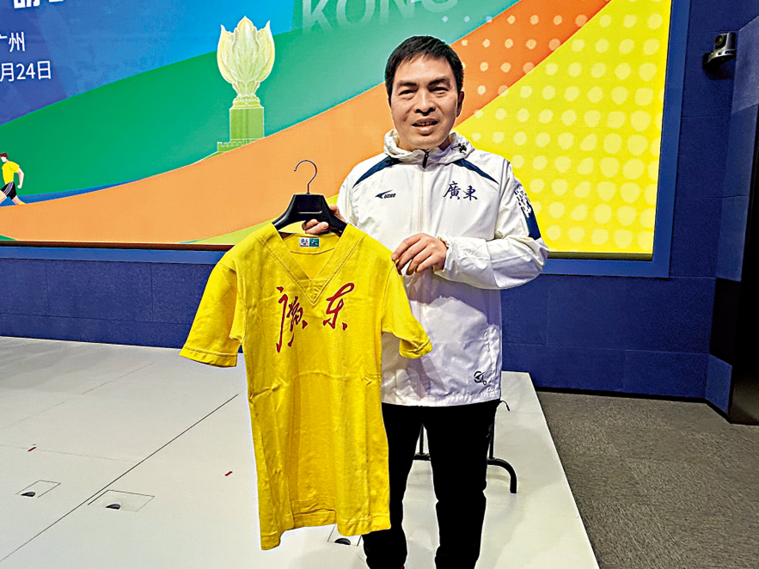 　　圖：朱成軍展示自己收集省港盃的珍藏，圖為容志行球衣。\大公報記者敖敏輝攝