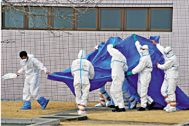 　　圖：2011年福島核災發生後，身着防護服的日本自衛隊員轉移傷者。\法新社
