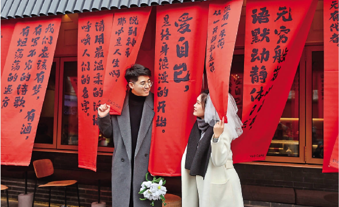 　　圖：在北京，一對情侶在街邊寫有「愛自己」的布幕下甜蜜合照。/新華社