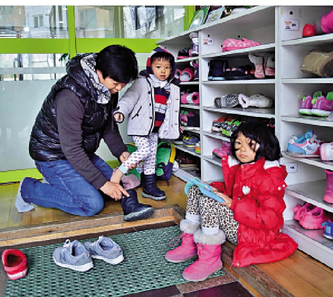 　　圖：韓國一名父親在首爾一家託兒所為孩子穿鞋。\法新社