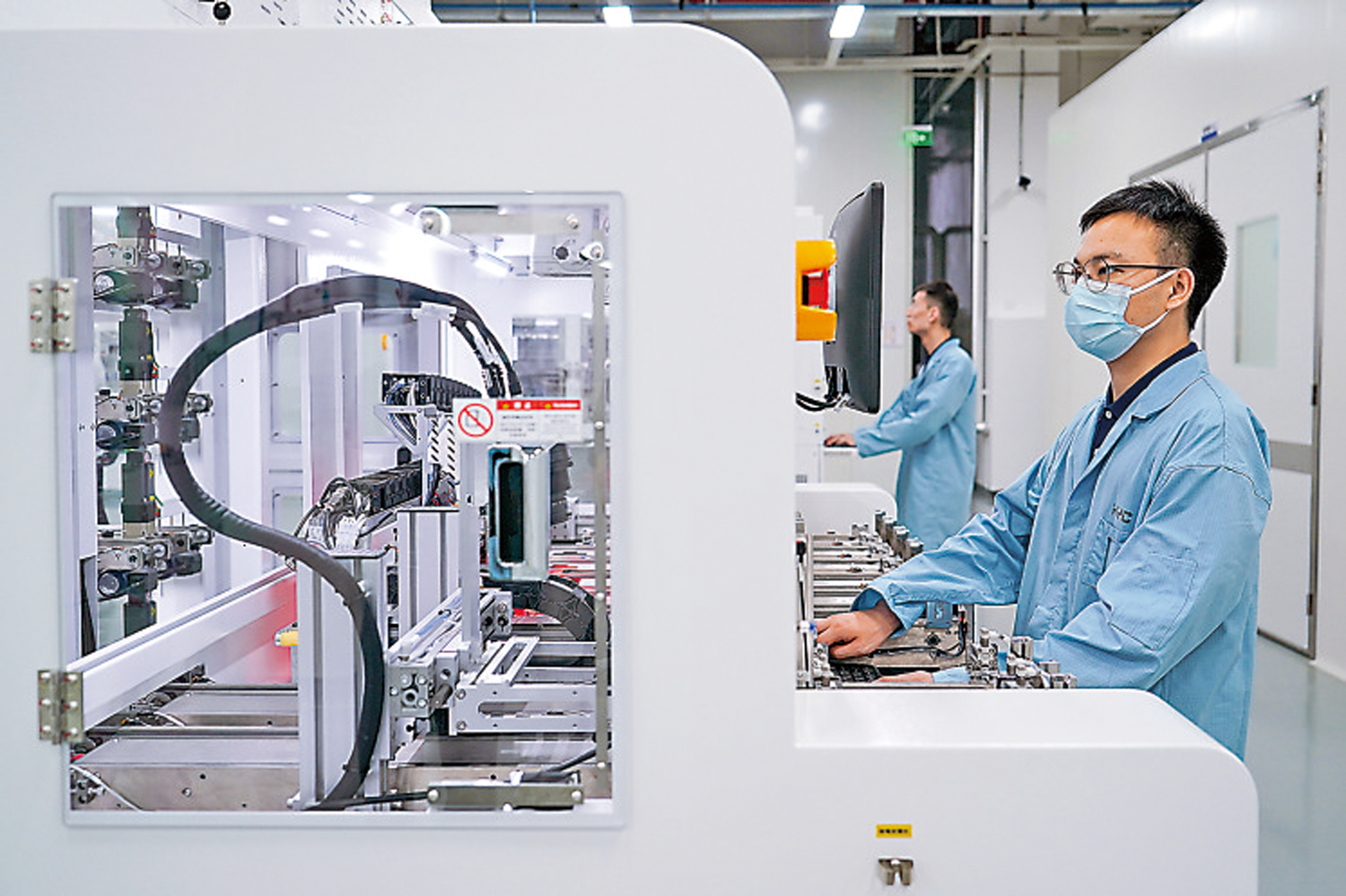 　　圖：蘇州一家科技公司工作人員在研發車間內操作先進封裝芯片測試機。\新華社