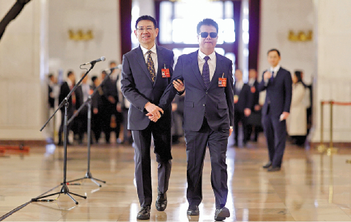 　　圖：全國人大代表黃立（左）攙扶全國人大代表、中國盲人按摩學會會長王永澄。\中新社