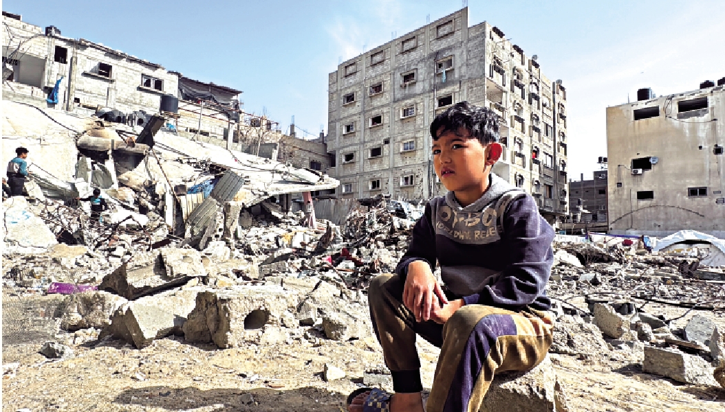 　　圖：一名巴勒斯坦男孩27日坐在以軍轟炸造成的廢墟上。\路透社