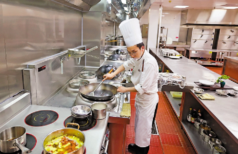 　　圖：廚師在博鰲亞洲論壇大酒店廚房裏使用電氣化改造後的電氣爐灶炒菜。\新華社