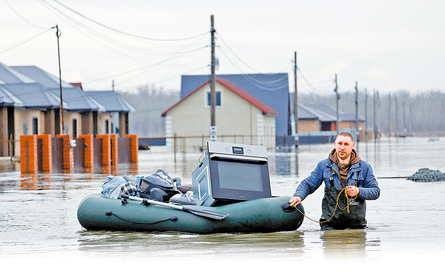 　　圖：俄羅斯奧倫堡州水淹街道，一名男子拖着家當艱難前行。\路透社