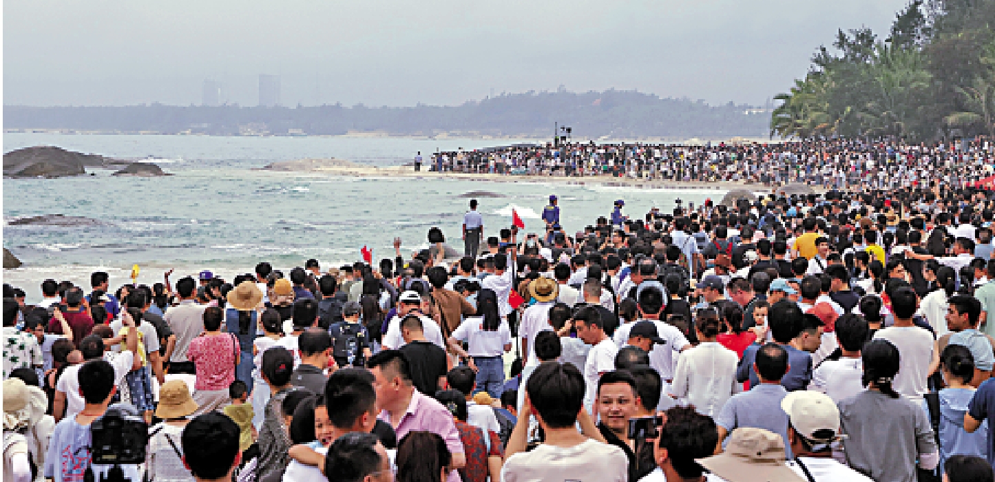 　　圖：群眾在海灘等待長征五號遙八運載火箭升空。\新華社