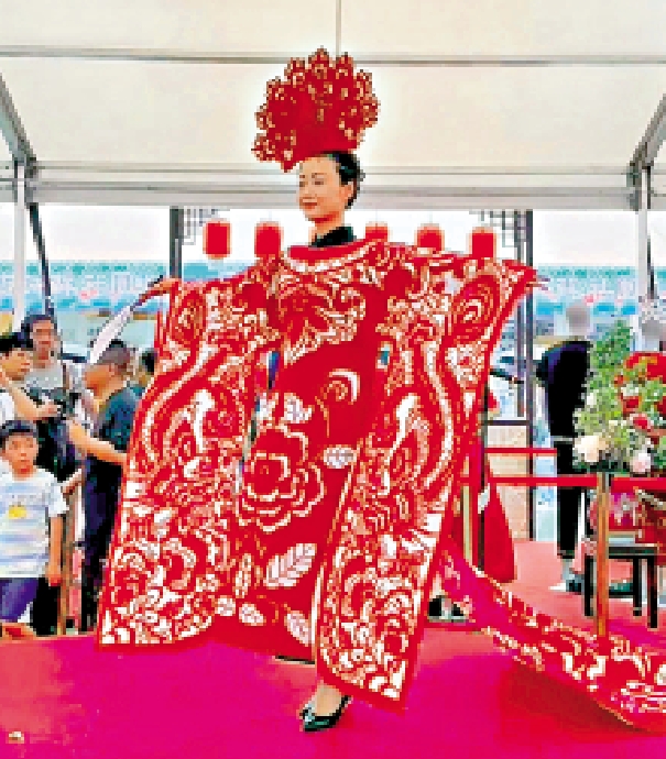 　　圖：日前家鄉市集嘉年華非遺展示區，有模特穿上剪紙服裝，吸引市民圍觀合照留念。