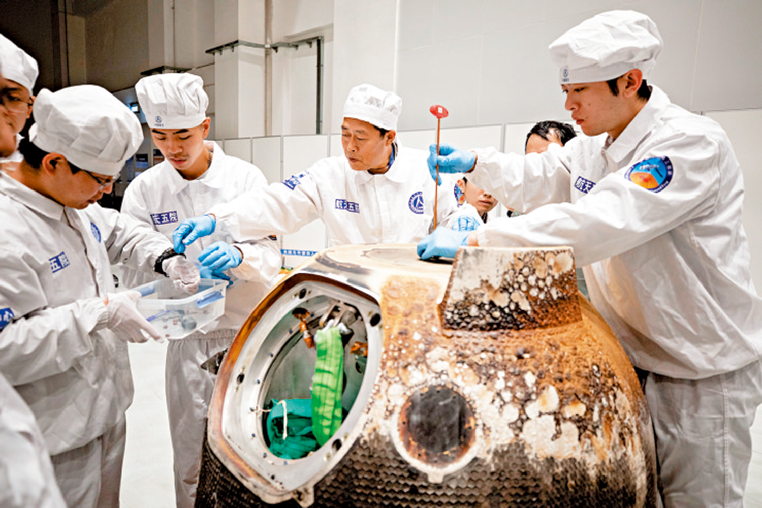 　　圖：2020年12月，科研人員從嫦娥五號返回器取出月壤容器。\新華社