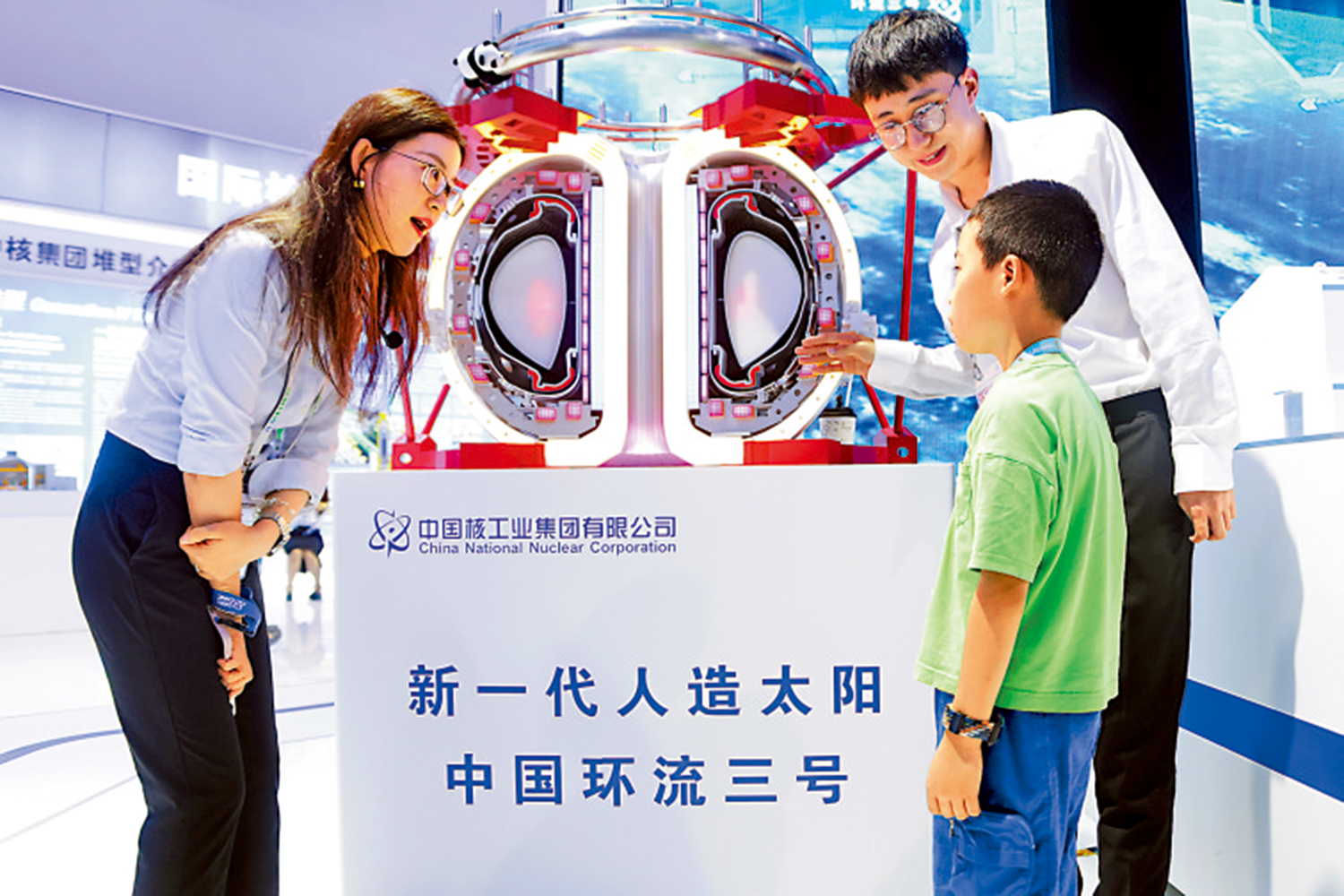 　　圖：14日，工作人員在北京國家會議中心為一名小觀眾介紹新一代人造太陽「中國環流三號」。\新華社