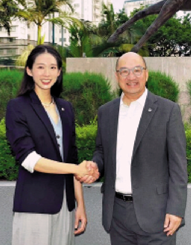 　　圖：江旻憓（左）與譚志源在賽馬會大樓外握手合照。