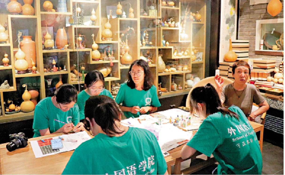 　　圖：阮氏微雕葫蘆第三代傳人阮琳（後排右一）講述刻葫蘆的知識。\大公報實習記者黃璟瑜攝