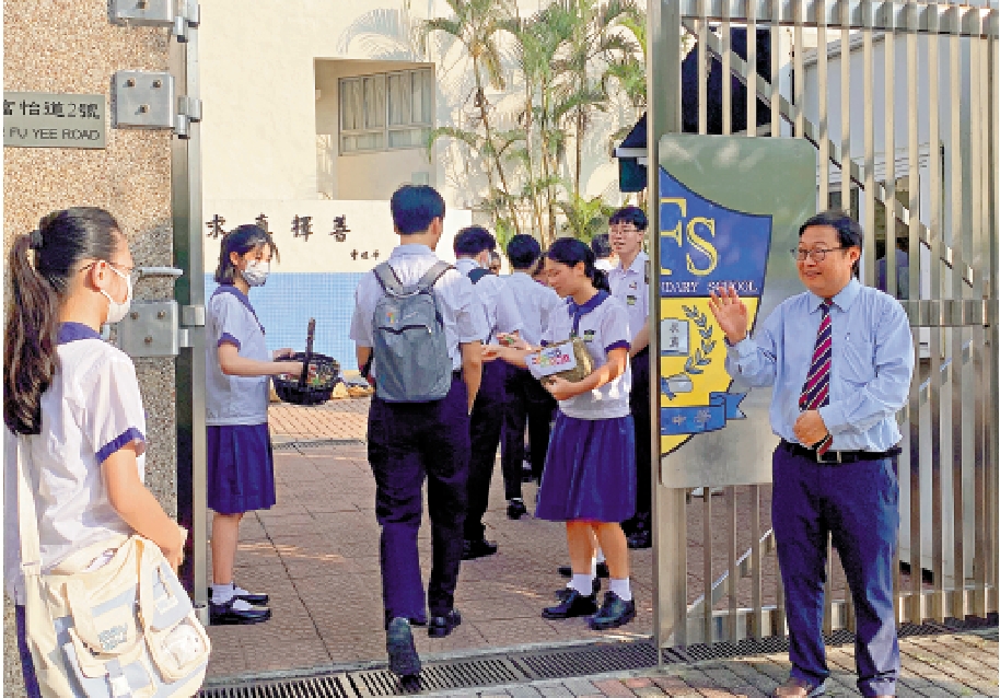 　　圖：福建中學（小西灣）昨日開學。新校長梁健文在校門迎接學生，每一位同學還獲贈送糖果歡迎。\大公報記者華夢晴攝