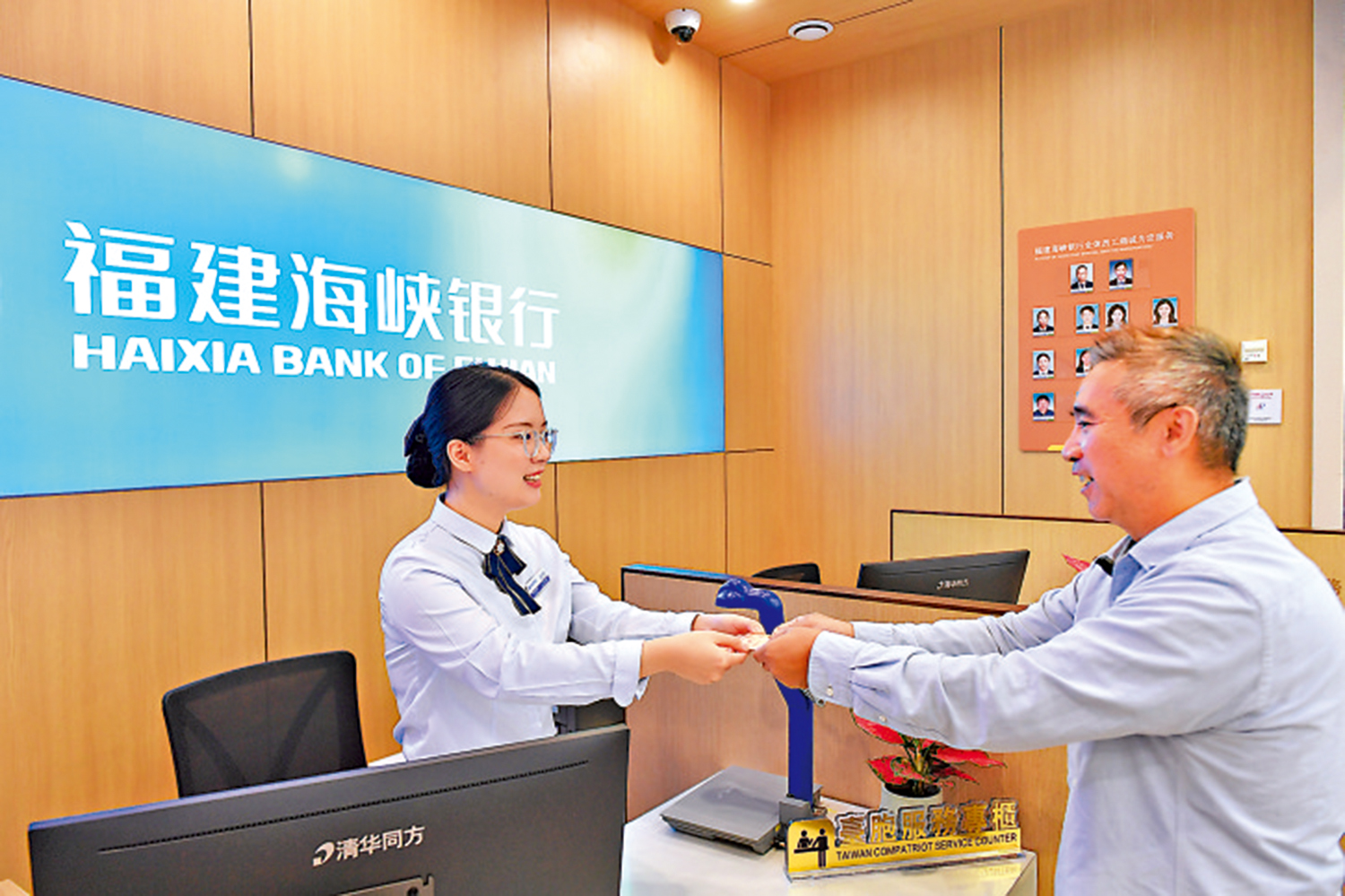 　　圖：林建雄（右）在福建海峽銀行福州閩江支行領取「福馬同城通」卡（金融卡）。\中新社