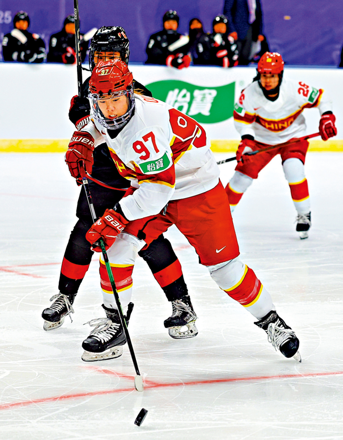 　　圖：中國女子冰球隊球員曲樂（前）在比賽中進攻。\新華社