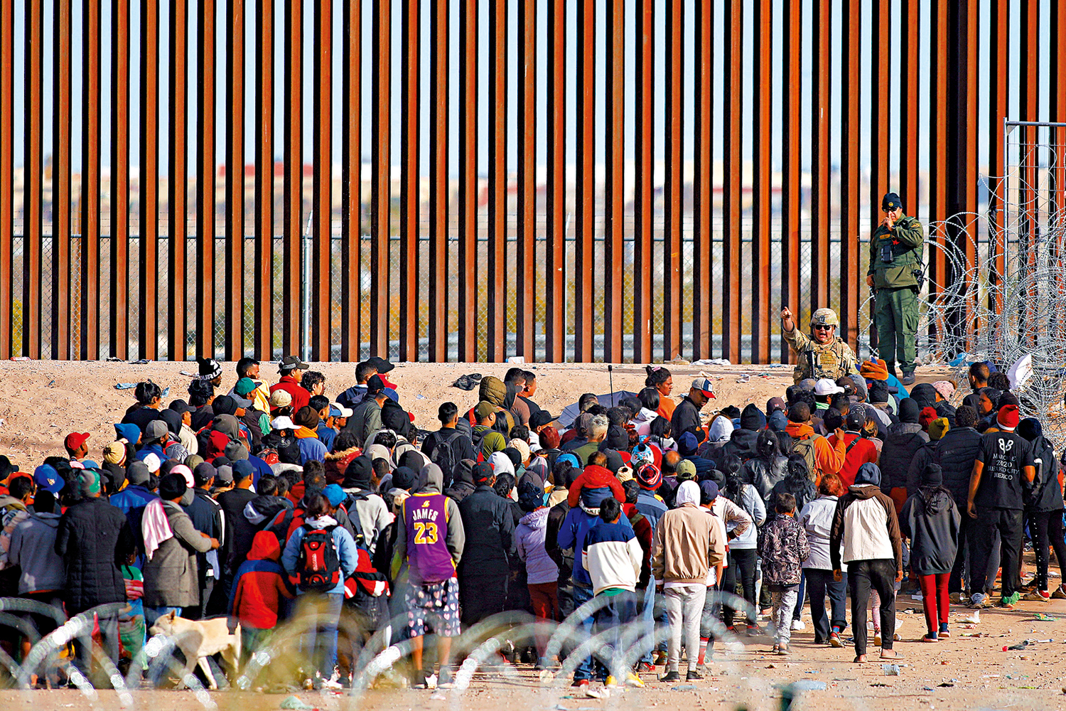 　　圖：2023年12月，非法移民聚集在美墨邊境牆附近請求庇護。\路透社