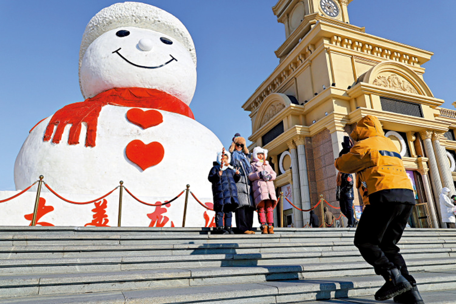 圖:來自浙江衢州的姜先生一家在哈爾濱群力音樂公園參觀網紅大雪人時拍照留念。\新華社