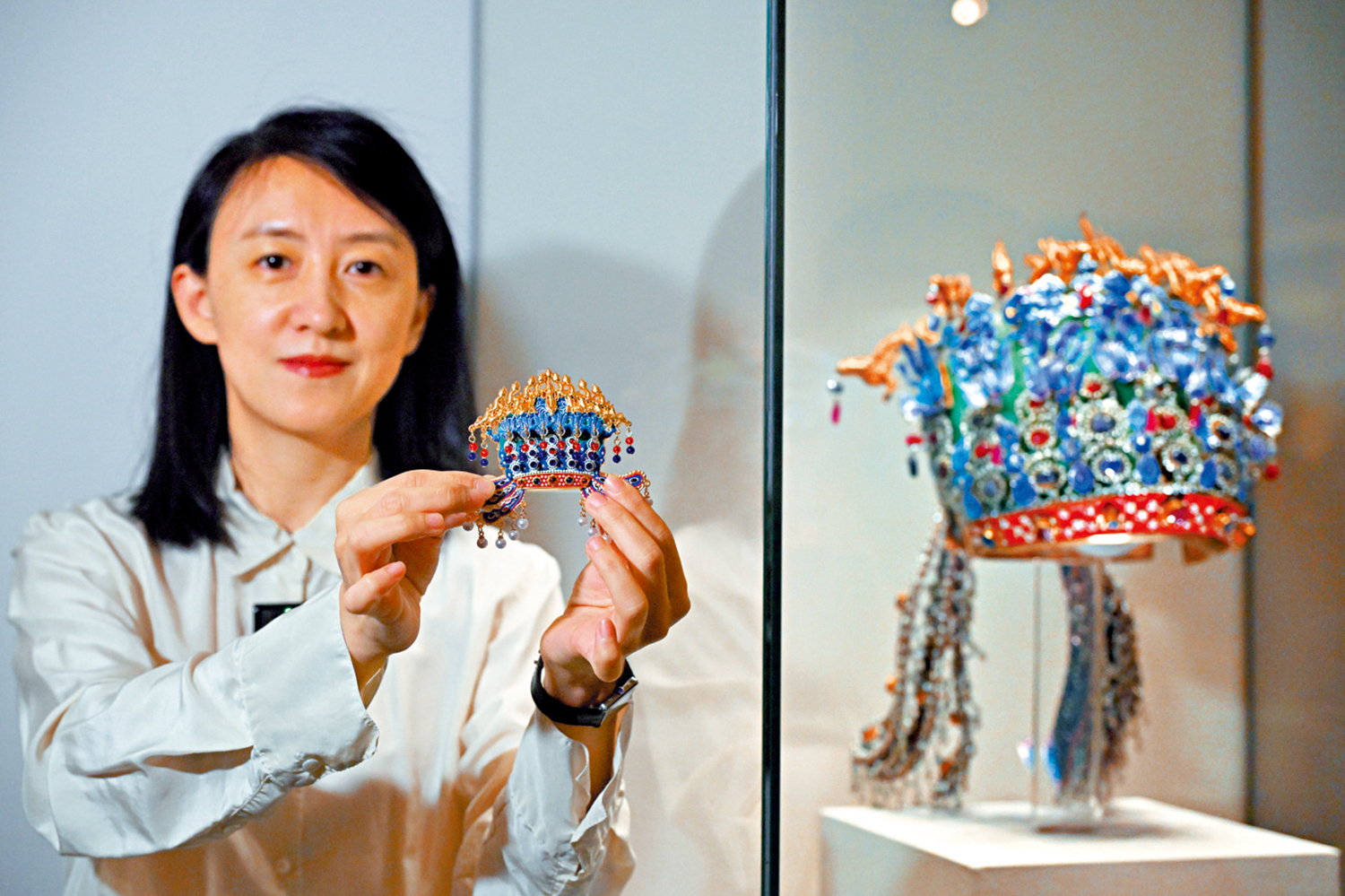圖:3月25日,參觀者在北京中國國家博物館展出的明孝端皇后九龍九鳳冠旁展示鳳冠冰箱貼。\新華社