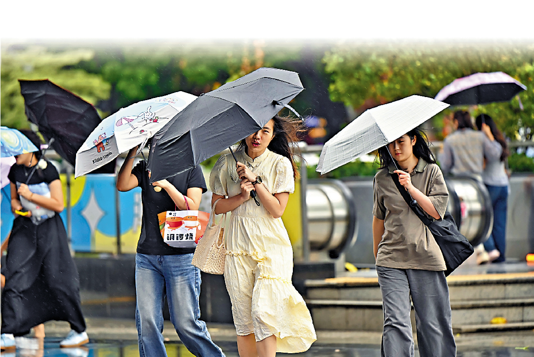 圖:4月12日,受強颮線(帶狀強對流雲系)影響,廣州市區出現大風、降水天氣。圖為市民風雨中出行。\中新社